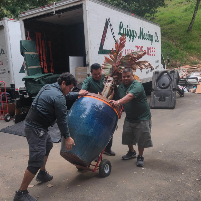 Two men wearing green shirts carrying a large green chair